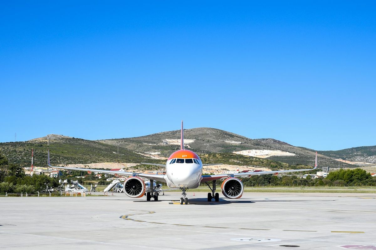 A passenger plane on the apron at Split Airport, with the hills of Kaštela behind