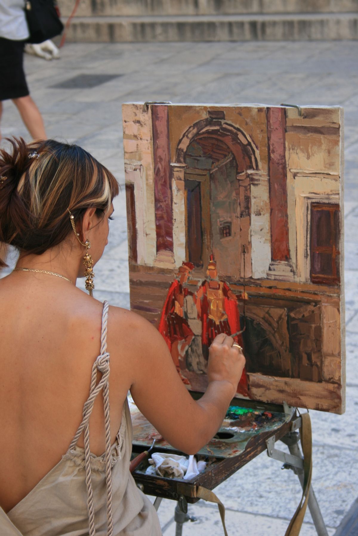 A painter at her easel in Split's old town, painting Roman soldiers in front of the palace